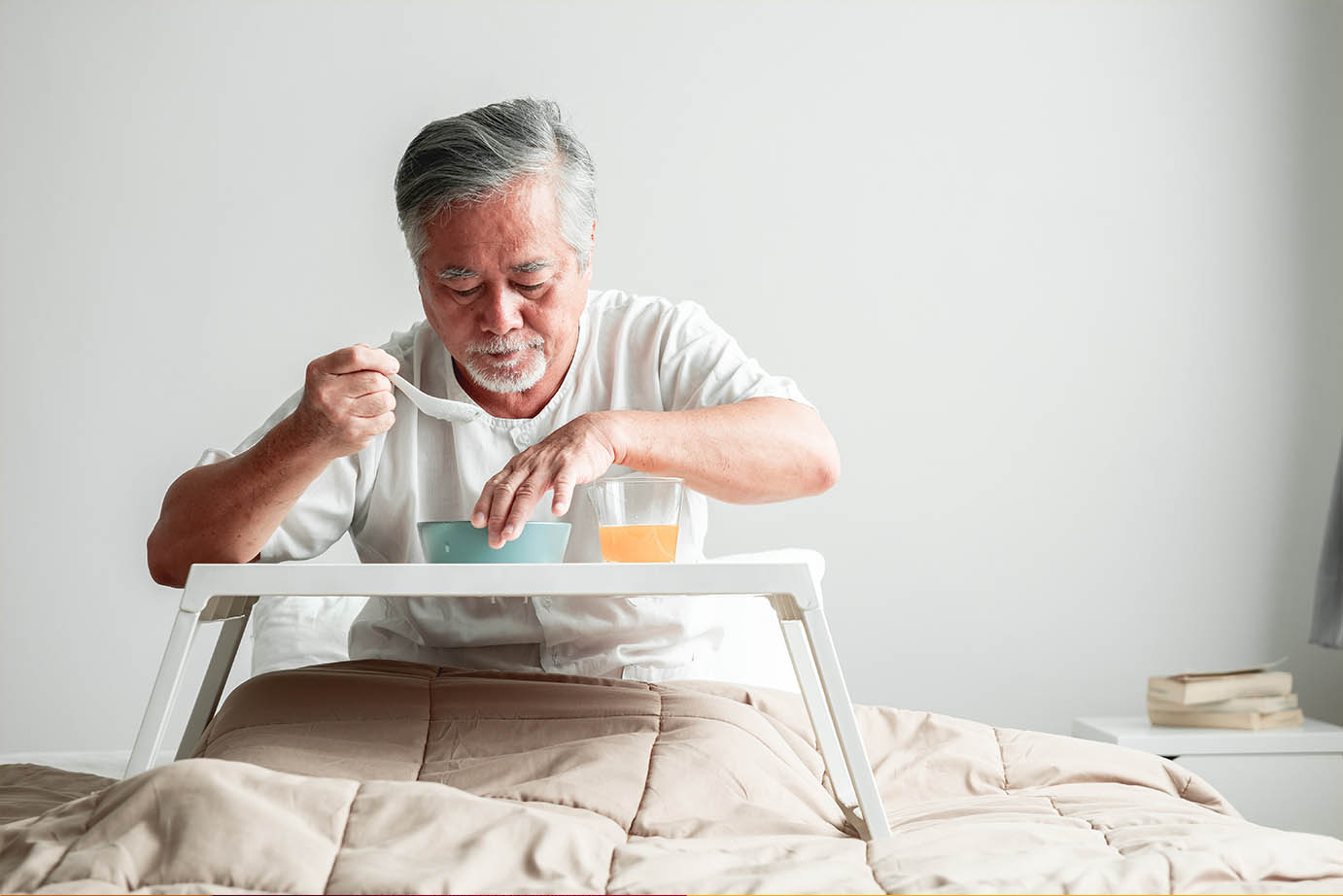 Senior man in bed eating soup