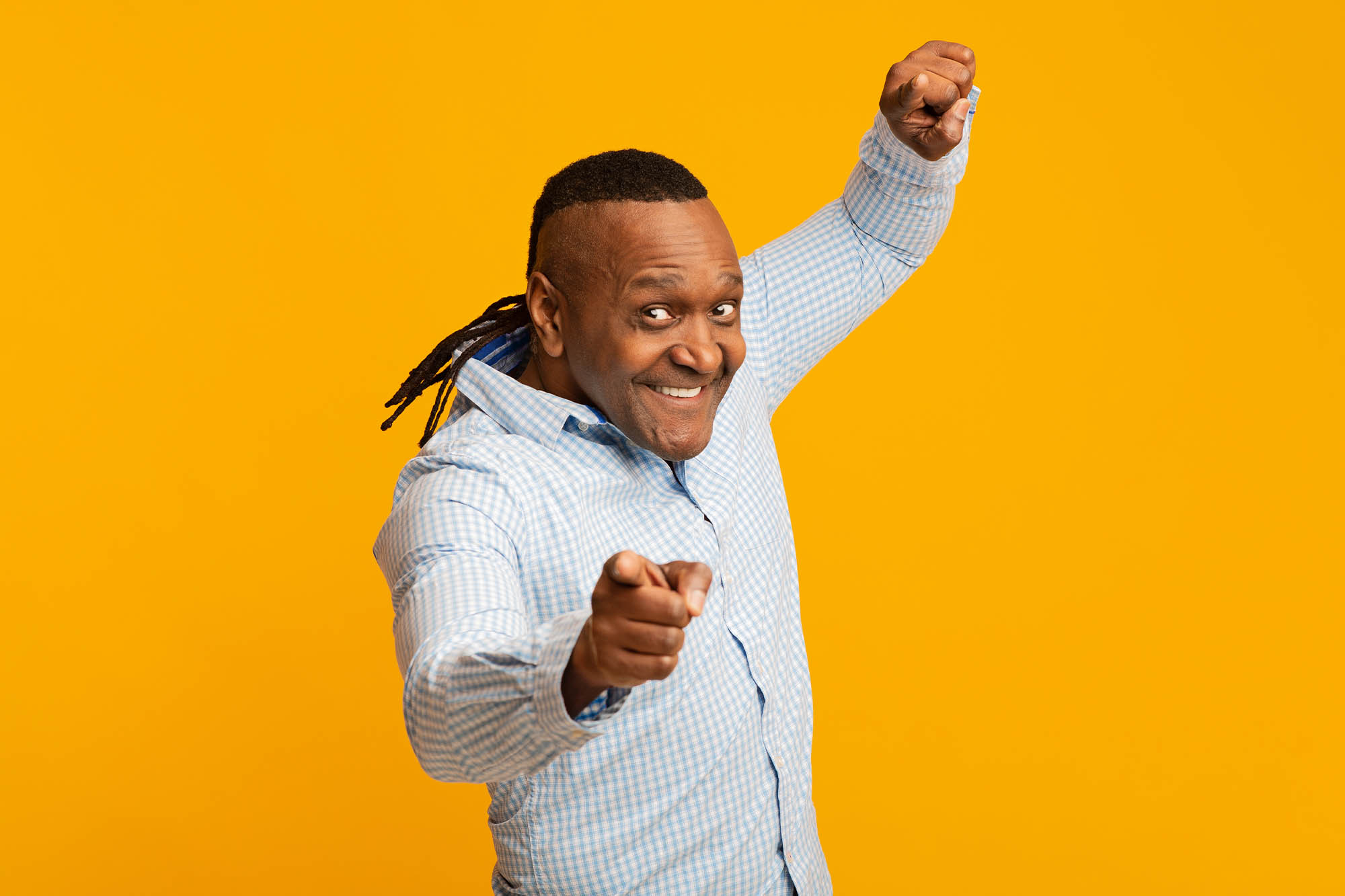 Senior man excited and pointing at camera on yellow background
